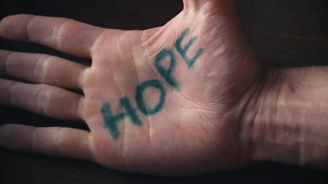 Struggling man write hope on his palm, desperation concept, life is hard but dont give up and hold on whatever happens