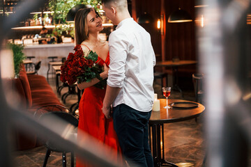 Man giving beautiful flowers. Romantic couple have dinner in the restaurant