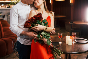 Man giving beautiful flowers. Romantic couple have dinner in the restaurant