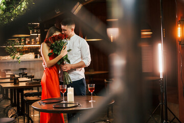 Standing with flowers. Romantic couple have dinner in the restaurant