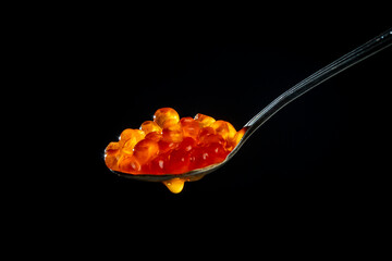 Fresh red caviar in a spoon on a black background