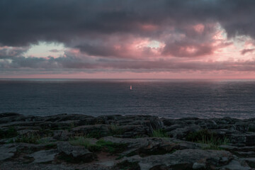 Beautiful cloudy sunset on the ocean with calm water and cliffs