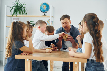 Exploring puzzle toy. Group of children students in class at school with teacher