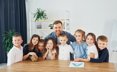 Standing and posing. Smiling together. Group of children students in class at school with teacher