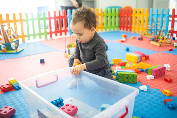 Toddler boy plays with colorful plastik blocks at children playroom