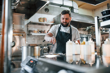 Pouring some salt. Professional chef preparing food in the kitchen