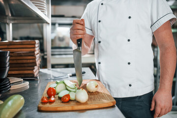 Man is making salad. Professional chef preparing food in the kitchen