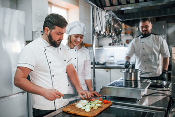Team making salad. Professional chef preparing food in the kitchen