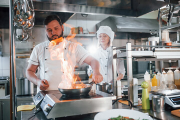 Fototapeta na wymiar Flames in the frying pan. Professional chef preparing food in the kitchen