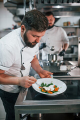 Two brothers is making salad. Professional chef preparing food in the kitchen