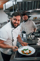 Two brothers is making salad. Professional chef preparing food in the kitchen