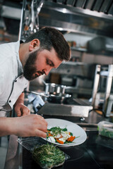 Two brothers is making salad. Professional chef preparing food in the kitchen