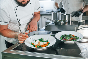 Two men is making salad. Professional chef preparing food in the kitchen