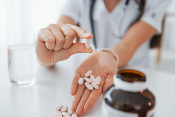 Pills in the hand. Professional medical worker in white coat is in the office