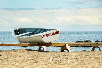 Looking out from the public swimming beach on Toronto's Centre Island at Lake Ontario with a tradtional wooden rescue skiff, still used by city lifeguards. in the foreground.  Room for text.