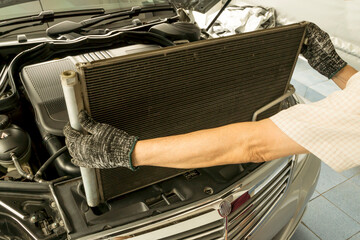 Auto mechanic remove air conditioning condenser to maintenance, Car maintenance service. - obrazy, fototapety, plakaty