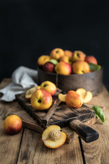 Peaches on a dark wooden board, with a peach cut in half, with a peach stone. A composition with ripe juicy peaches collected for consumption. Fresh organic fruits