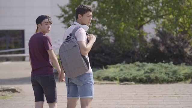 Homophobic teenager girl insulting and making fun of gay couple. Students walking holding hands in a park.