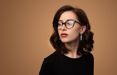 Serious businesswoman in glasses looking away in beige studio