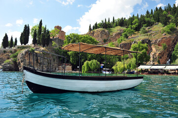 Boat on lake Ohrid. Church and small harbor in the background. Horizontal image.
