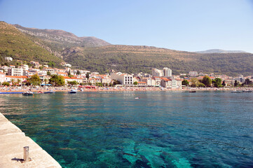 View from pier towards little idyllic village Petrovac in Montenegro.  Clear summer day and turquoise blue ocean.