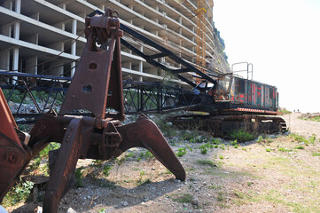 Abandoned crane in front of unfinished hotel in Montenegro. Rusty machine and empty abandoned...