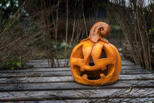 Halloween and darkness theme. Head pumpkin Jack-o'-lantern made of stucco and have a solar cell placed on old pine pallets and dark garden atmosphere with background and copy space.