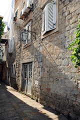 Old brick building with cast iron doors with faded paint in Budva, Montenegro. Vertical street view.