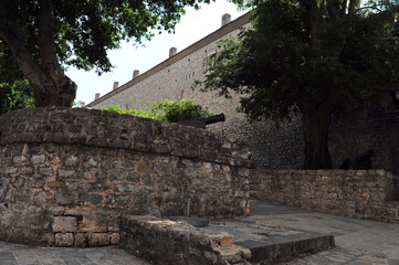 Fototapeta na wymiar Entrance to the fortress Citadela in Budva, Montenegro. Brick walls with canon. Horizontal photo.