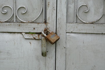 Old rusty iron lock on gray metal gates.