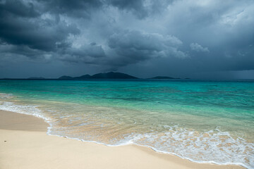 Jost Van Dyke surrounded by tropical squall clouds viewed across turquoise Caribbean waters from...