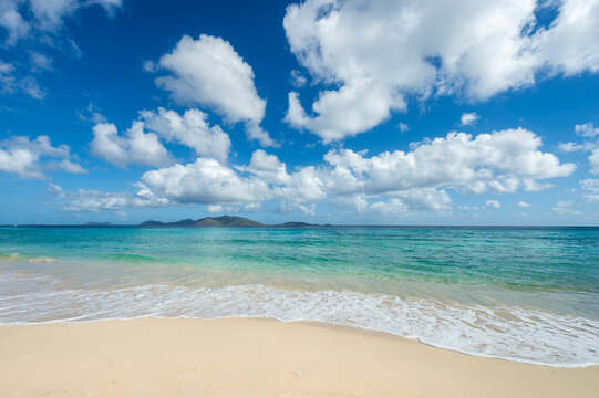Jost Van Dyke viewed across turquoise Caribbean waters from the white sands of Apple Bay Beach on Tortola, BVI 