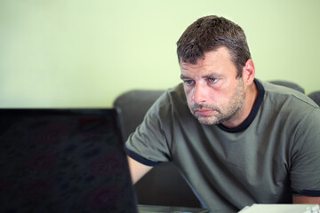 Close portrait of a handsome caucasian bearded man, casual clothing, working from home on a laptop. Copy space