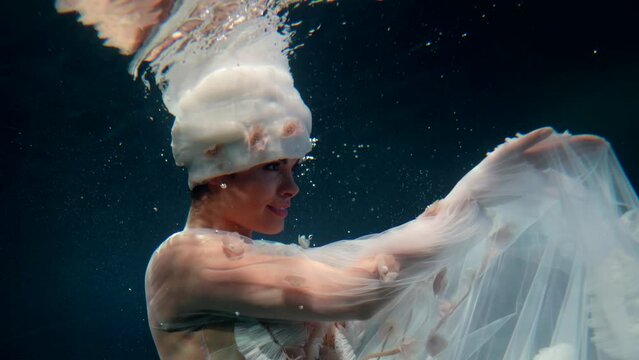 fantastic underwater shot with flower fairy in mysterious deepness, pretty lady in white dress