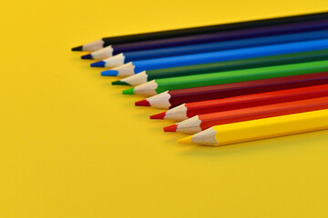 Colored pencils for drawing are depicted on a yellow background. The pencils are sharpened. A great set for drawing.