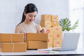 SME entrepreneur Business Young Asian freelance girl works with a laptop and box at home, about eCommerce, business, seller, Asian, employee, entrepreneur, box, merchant, Online SME business ideas,
