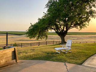 White lounge chair on a grassy knoll at sunset in Oakdale, California.