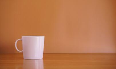 Pink ceramic coffee cup on wood table with brown background