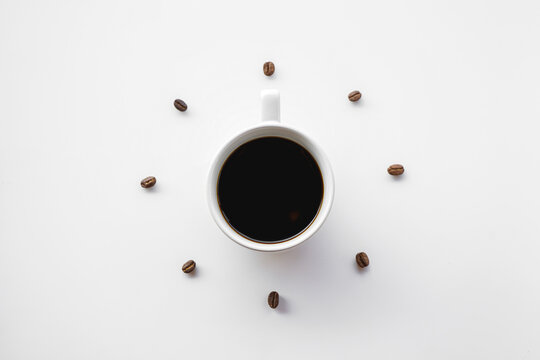 Black coffee cup on white background with Coffee beans arrange as forming clock face at 12 o'clock