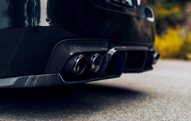 Fototapeta na wymiar Quad exhaust pipes on a black car with carbon fiber accents