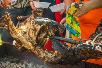 Volunteers distribute food to the poor outdoors, roast lamb on a spit selective focus