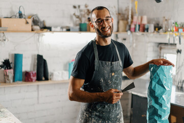 Artisan sculptor artist of Arab appearance smiling at the camera against the backdrop of the...