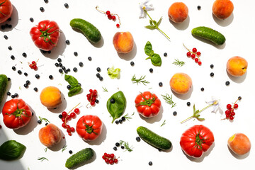 pattern of vegetables and fruits on a white background in daylight. Tomatoes, cucumbers, herbs, berries and apricots lie on the table