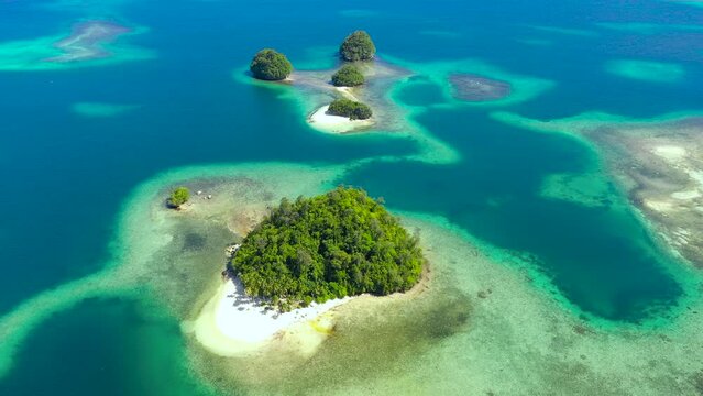 Aerial view of Tropical island with sand beach, palm trees by atoll with coral reef. Britania Islands, Surigao del Sur, Philippines.