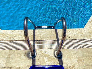 seaside vacation by the pool. deep pool with clear, blue water with bleach inside. metal ladder for...
