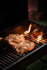 Flame grill BBQ steak meat on charcoal fire stove in dark tone high contrast close up
