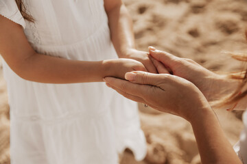 Crop mother holding hands of daughter