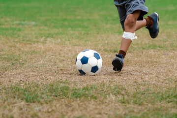 Football soccer children training class. Kindergarten and elementary school kids playing football in a field. Group of boys running and kicking soccer on sports grass pitch. Selective focus on ball.