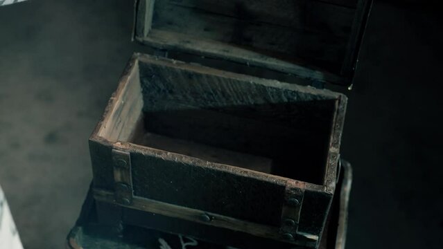 High angle shot of a person's hands opening a rusted wooden empty treasure chest