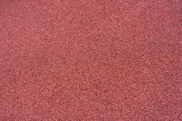 The texture of red rubber crumbs at a sports stadium